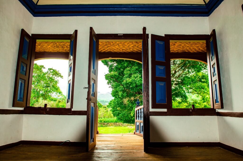 Terapias y Sesiones Inviting interior with classic wooden doors and vibrant outdoor greenery, showcasing colonial architecture.