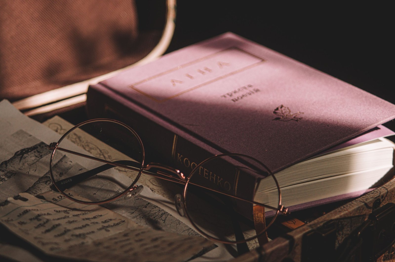 A vintage setting with eyeglasses resting on an open book and travel maps, suggesting exploration and study.