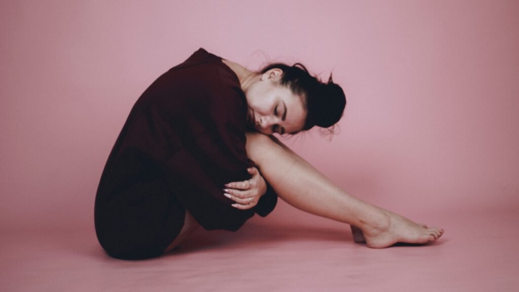 Terapias y Sesiones Portrait of a serene woman sitting with eyes closed in a minimalist studio setting.