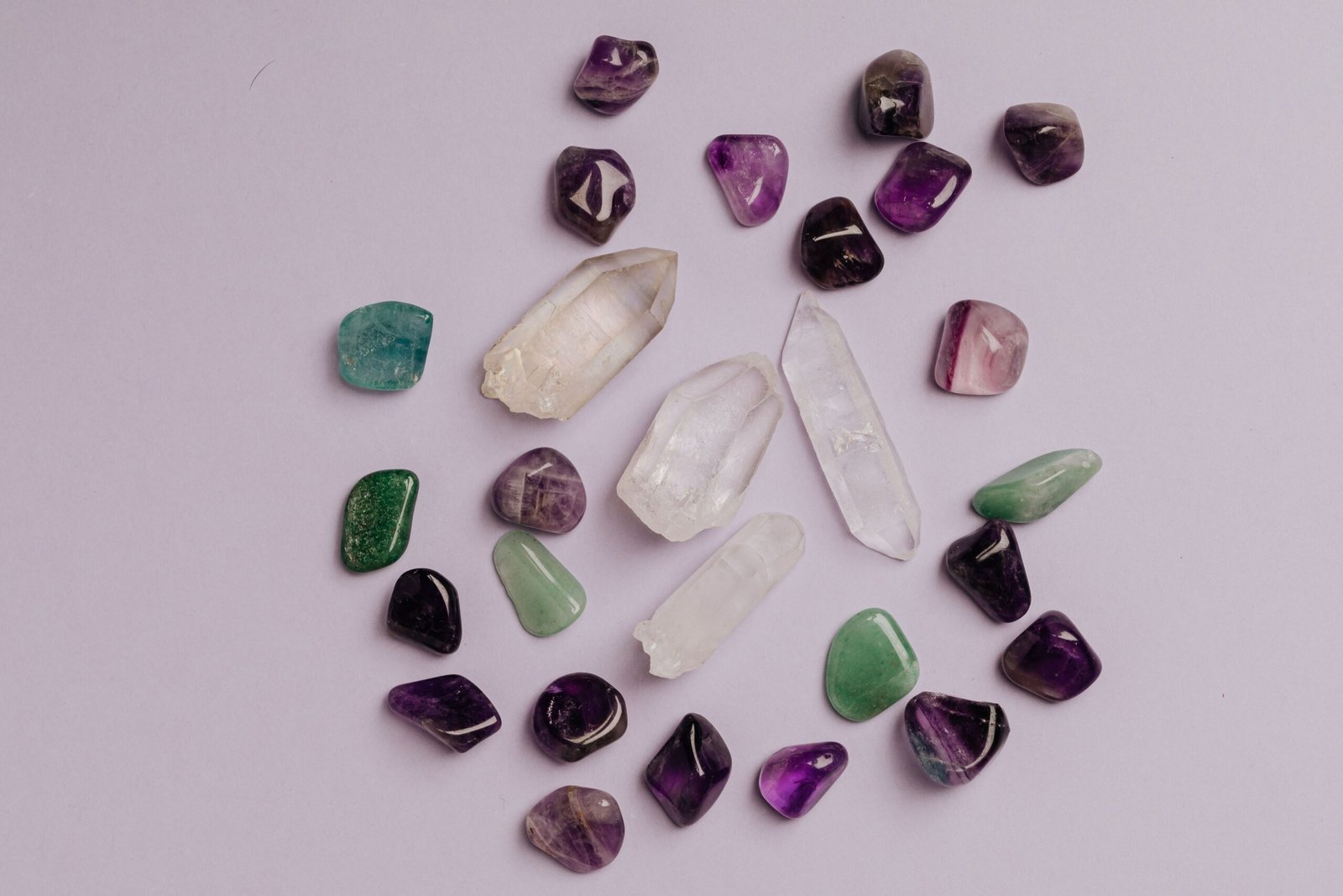 A collection of assorted gemstones including amethyst, jade, and quartz arranged in a flat lay.
