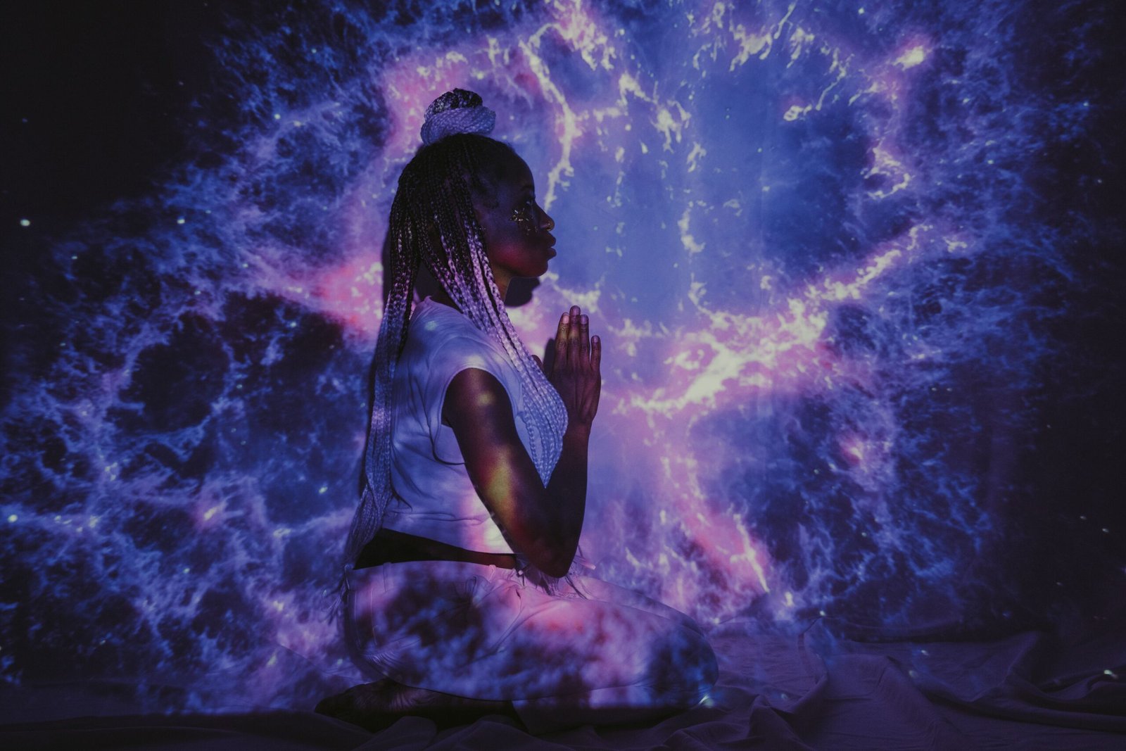 A woman kneels in a galaxy projection, creating a mesmerizing cosmic backdrop.