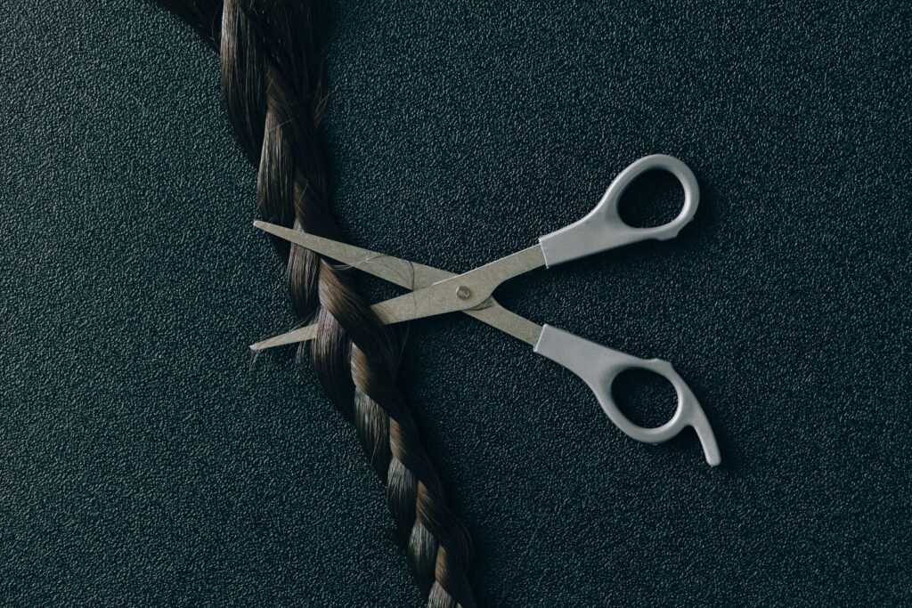Terapias y Sesiones Artistic display of scissors poised to cut a braid against a dark textured backdrop.