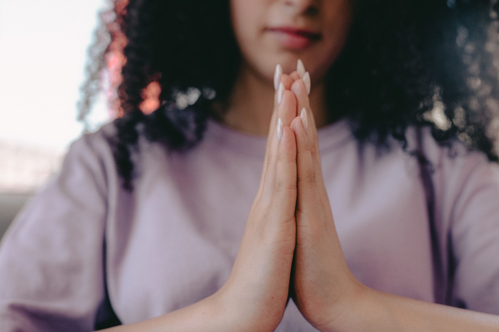 A serene close-up image of a woman with hands in a praying position, emphasizing mindfulness and calmness.